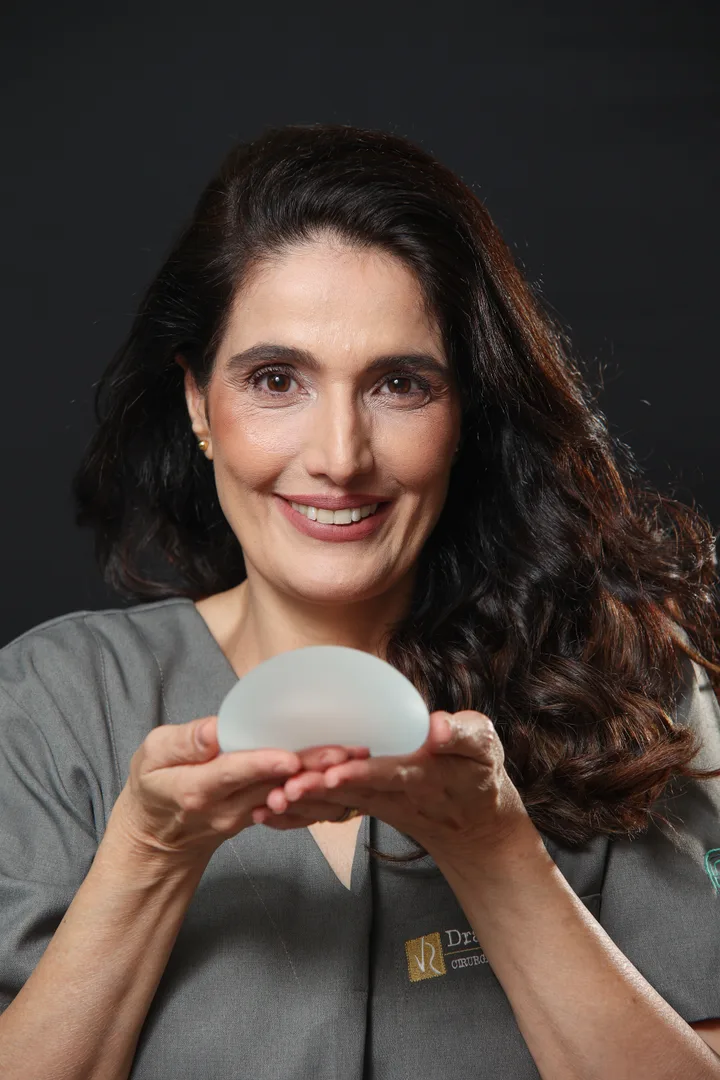 Dra. Vanessa Rajo segurando uma prótese mamária em ambiente de estúdio